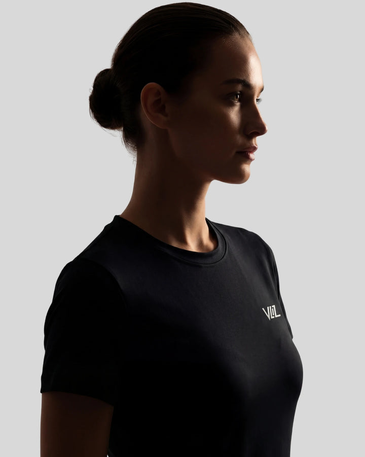 Woman wearing a black t-shirt with a logo on a gray background