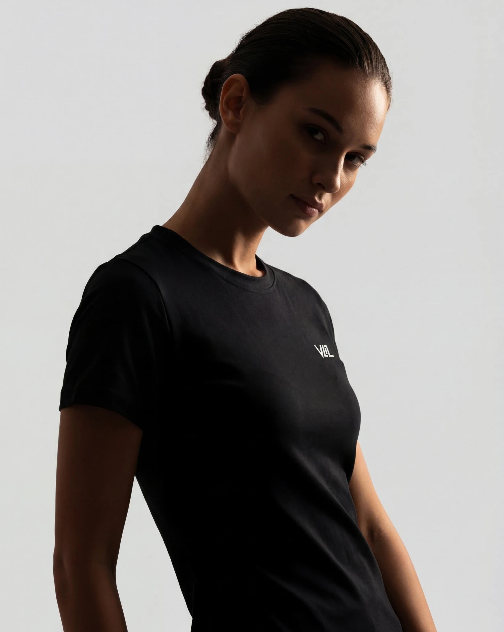 Woman wearing a black t-shirt with a logo on a gray background