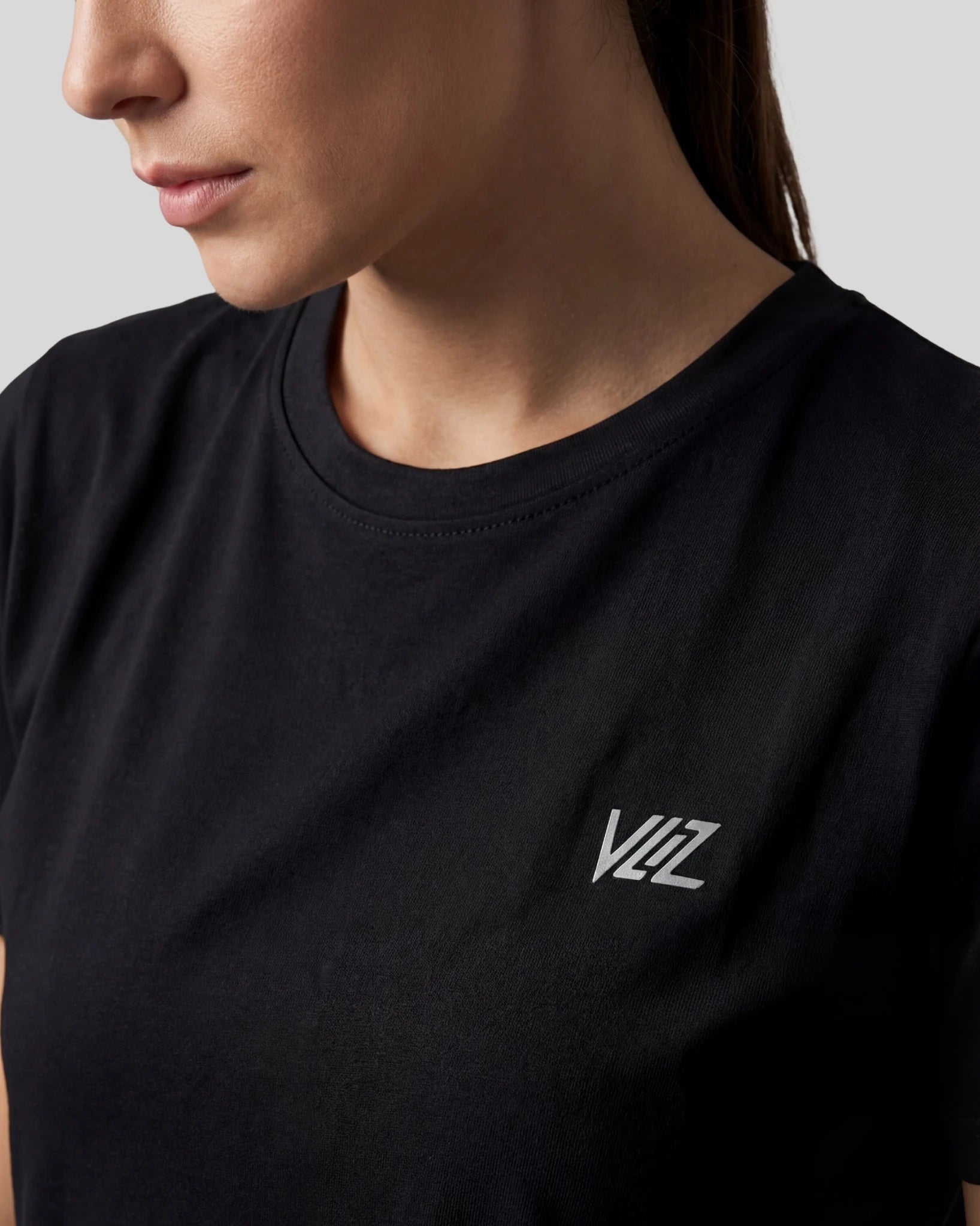 Person wearing a black t-shirt with a logo on a gray background