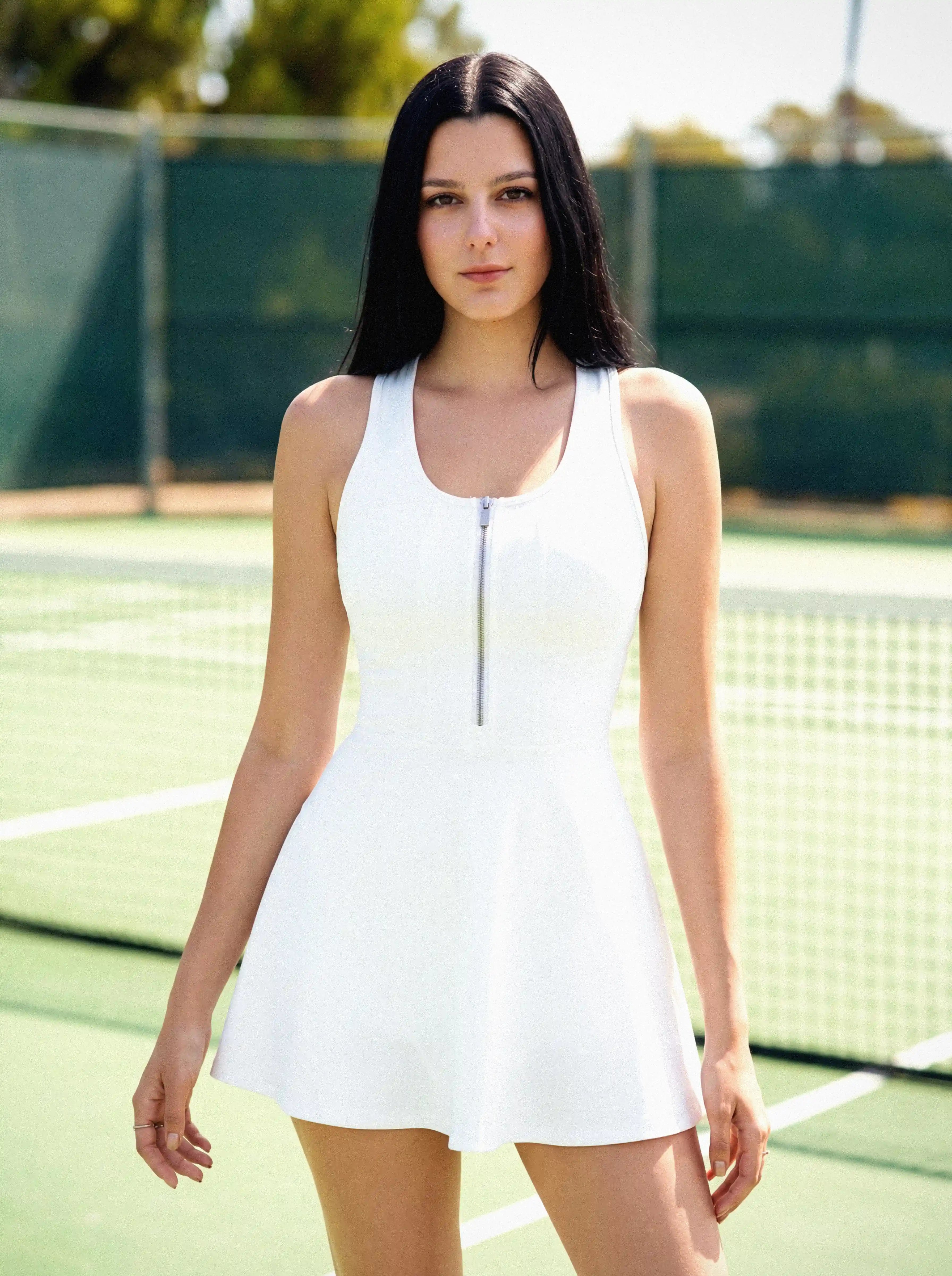 Woman in a white dress standing on a tennis court